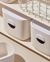 Close up of two Cream Medium Storage Bins on a cream surface.
