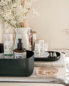 Close up view of the Small Dark Green Storages Bins with beauty products on a cream background.