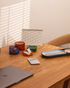 The Multi - Color Storage gems with stationary stored in it on a wooden surface.