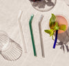 Over head shot of the Glass Straws in Cool Set with a cocktail next to it on a white background.