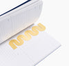 Brass Bookmark in Wave inside a Planner on a white background.