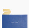 Brass Bookmark in Wave inside a Planner on a white background.