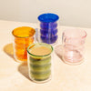 Different colored Double Wall Groovy Cup one filled with tea on a cream surface.