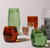 Different color and sizes of Century Glasses filled with water on a cream background.