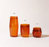 A 16 oz , 12 oz and 6 oz Amber Century Glasses lined up on a cream background.