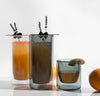 A 6 oz and two 16 oz Gray Double Wall Glasses filled with juice on a grayish background.