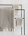 The Onsen Oatmeal Waffle Bath Sheet on a metal towel rack. 