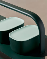 Close up view of two Dark Green Small Storage Bin with Mint Lid on a dark green surface.