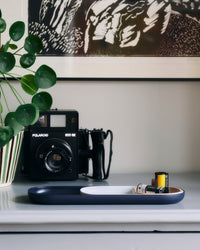 Side view of the Open Spaces Navy Nesting tray with camera reels on it on a white background.