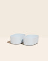 Two Small Light Blue Storages Bins with no  lids on a cream background.