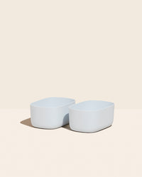 Two Small Light Blue Storages Bins with no  lids on a cream background.