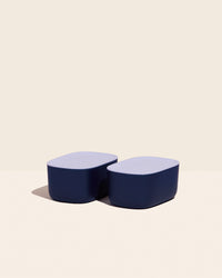 Two Small Navy Storages Bins with plastic Lavender lids on a cream background.
