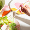 A hand holding the Bamboo Fork over a salad. 